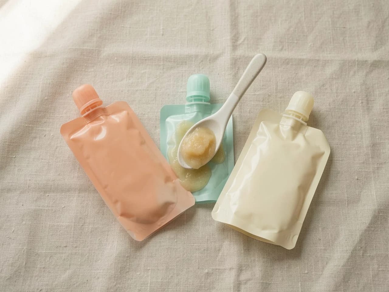 Une rangée de gourdes pressables pour bébés sur une surface claire, illustrant les produits testés dans l'enquête Greenpeace de mai 2026 qui a trouvé des milliers de particules de microplastiques par gourde